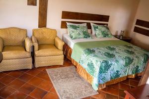 a bedroom with a bed and two chairs at Sunny Palm Villas in Laborie