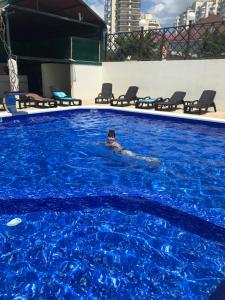 ラザレフスコエにあるHotel Lauraの青い大きなプールで泳ぐ男