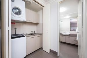 a white kitchen with a sink and a washing machine at Fremantle Harbourside Luxury Apartments in Fremantle