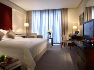 a hotel room with a large bed and a desk at Howard Johnson Parkland Hotel Dalian in Dalian