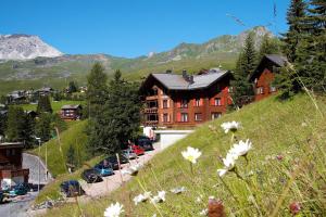 阿罗萨Hotel Sonnenhalde, Arosa的山坡上一座建筑物,有车辆停放