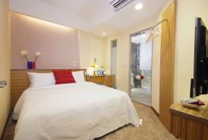 Golden Hotel في تايبيه: غرفة نوم بسرير ابيض ومخدة حمراء