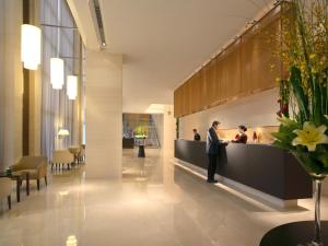 a man standing at a counter in a lobby at Howard Johnson Parkland Hotel Dalian in Dalian