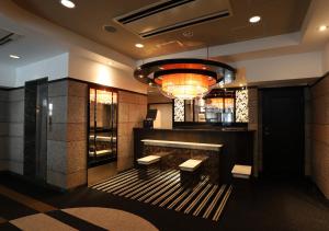 a lobby with a bar with benches and a chandelier at APA Hotel Chiba Chuo Ekimae in Chiba