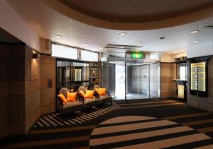 un vestíbulo con un sofá con almohadas naranjas en APA Hotel Chiba Chuo Ekimae, en Chiba