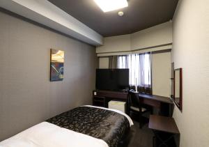 um quarto de hotel com uma cama, uma secretária e uma televisão em APA Hotel Chiba Chuo Ekimae em Chiba