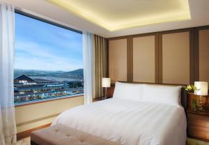a bedroom with a bed and a large window at LOTTE City Hotel Gimpo Airport in Seoul