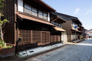 un vecchio edificio con un cancello su una strada di 民家ホテル「金ノ三寸」(かねのさんずん） a Takaoka