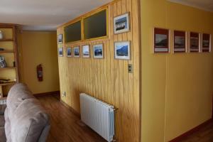 uma sala de estar com um sofá e quadros na parede em Asói Hostal em Puerto Natales