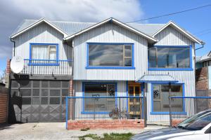uma casa branca e azul com acentos azuis em Asói Hostal em Puerto Natales