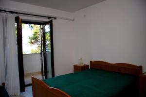 1 dormitorio con cama verde y puerta corredera de cristal en Apartments DeMar - 70m from sea, en Splitska