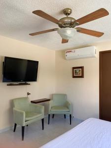 a bedroom with a ceiling fan and two chairs and a desk at Casa Oyamel, Private Room in the heart of cancun in Cancún