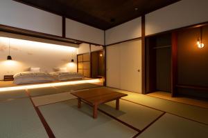 a bedroom with two beds and a coffee table at 民家ホテル「金ノ三寸」(かねのさんずん） in Takaoka