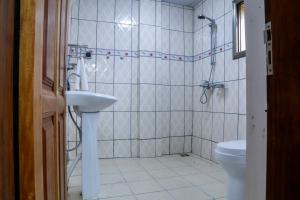 een badkamer met een douche, een wastafel en een toilet bij Hôtel Libertis in Douala
