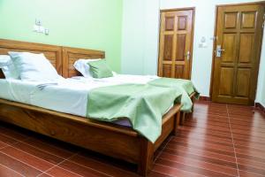 ein Schlafzimmer mit einem Bett mit einer grünen Decke darauf in der Unterkunft Hôtel Libertis in Douala