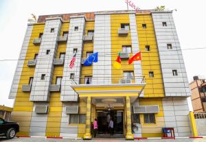 杜阿拉Hôtel Libertis的黄色和白色的建筑,上面有旗帜