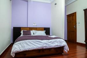 een slaapkamer met een groot bed met een houten hoofdeinde bij Hôtel Libertis in Douala