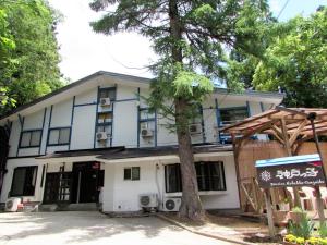 a building with a tree in front of it at Pension Kobekko in Otari