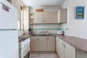 a kitchen with white cabinets and a sink and a stove at Indian Ocean Views in Fremantle