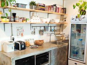 a kitchen with a counter with a sink and a refrigerator at HOLY SHEET Hostel in Bangkok