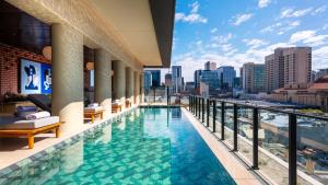 a swimming pool on the roof of a building with a city skyline at Hotel Indigo Adelaide Markets by IHG in Adelaide