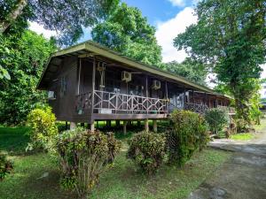 a large wooden house with a balcony and trees at Benarat Lodge in Mulu