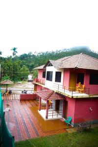 a pink house with a balcony and a patio at Vamoose Balgal Homestay in Kalasa
