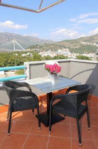 einen Terrassentisch mit 2 Stühlen und eine Vase aus Blumen in der Unterkunft Villa Antea Apartments in Dubrovnik