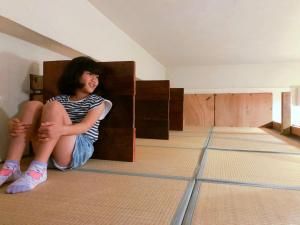 a girl sitting on the floor in a room at Guest House Cam Cam Okinawa in Naha