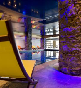 a lobby with a yellow chair and a stone wall at CGH Résidences & Spas Le Cristal de l'Alpe in L'Alpe-d'Huez