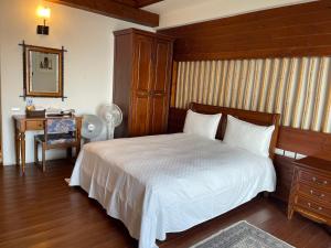 a bedroom with a white bed and a table and a desk at Sheep Village Country Homestay in Renai