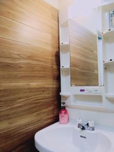 a bathroom with a white sink and a wooden wall at Guest House Cam Cam Okinawa in Naha