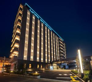un edificio iluminado con un estacionamiento delante de él en Hotel Route Inn Noda -Kokudo 16 Gouzoi- en Noda