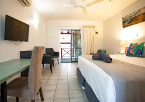 a bedroom with a bed and a desk and a television at Kimberley Croc Motel in Kununurra
