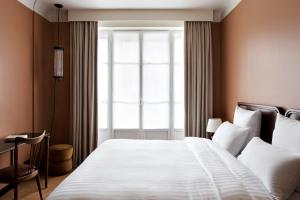 Un dormitorio con una gran cama blanca y una ventana en Hotel Rochechouart - Orso Hotels, en París