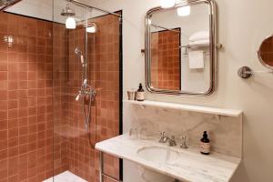 La salle de bains est pourvue d'un lavabo et d'une douche. dans l'établissement Hotel Rochechouart - Orso Hotels, à Paris