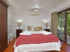 a bedroom with a bed with a red and white blanket at Olive Grove 1 Studio in Pokolbin