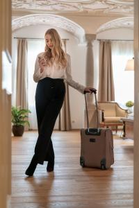 a woman standing in a room with a suitcase at Stadthotel Styria in Steyr