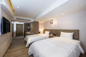Habitación de hotel con 2 camas y TV de pantalla plana. en Lan Kwai Fong Garden Hotel en Chiayi