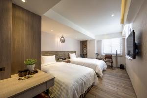 a hotel room with two beds and a television at Lan Kwai Fong Garden Hotel in Chiayi City