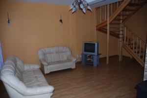 sala de estar con sofá, silla y TV en Amber Cottage, en Jūrmala