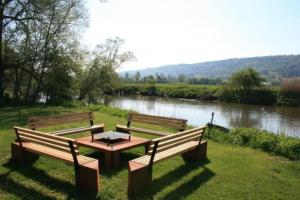 2 bancs et une table de pique-nique à côté d'une rivière dans l'établissement NATURAMA BEILNGRIES - SchäferwagenDorf, à Beilngries