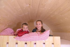 dos niños acostados en la cama en una tienda de juegos en NATURAMA BEILNGRIES - SchäferwagenDorf, en Beilngries