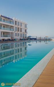 a pool of blue water in front of a building at Adan Beach Residence, Beach Front Apartments in Aourir