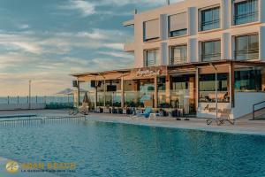 a hotel with a swimming pool in front of a building at Adan Beach Residence, Beach Front Apartments in Aourir