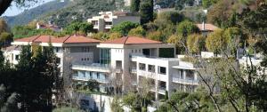 a large white building on a hill with trees at La Perle d'Eze - Aparthotel in Éze