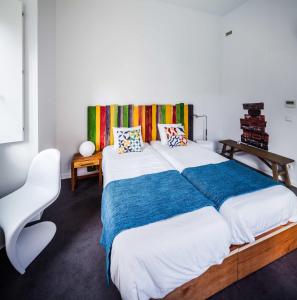 1 dormitorio con 2 camas y una silla blanca en Moon Hill By Joivy, en Sintra