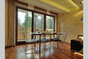 - une salle à manger avec une table, des chaises et des fenêtres dans l'établissement Komfortowe apartamenty u stóp Giewontu, à Kościelisko