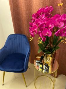 a blue chair and a vase of flowers on a table at ORKED BELLINA, 3 Bedroom apartment, near Pantai Batu Burok, NETFLIXWIFIYOUTUBE in Kuala Terengganu