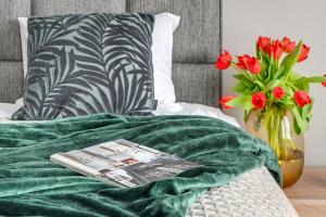 a green blanket on a bed with a vase of flowers at Premium Residence by Welcome Apartment in Gdańsk